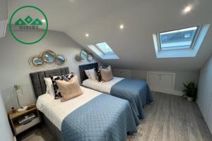 a attic bedroom with two beds and skylights at Aisiki Apartments at Stanhope Road, North Finchley, Multiple 2 or 3 Bedroom Pet Friendly Duplex Flats, King or Twin Beds with Aircon & FREE WIFI in Finchley