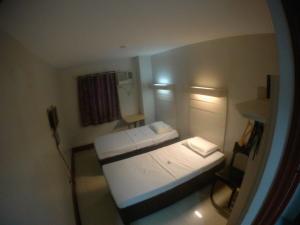 um pequeno quarto com uma cama e uma janela em D' Loft Inn CDO em Cagayan de Oro