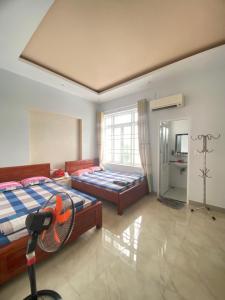 a bedroom with two beds and a fan in it at O Vững's Homestay in Vung Tau