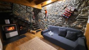 sala de estar con sofá azul y pared de piedra en Apimonte O Cantinho da Maria - PN Montesinho en Bragança