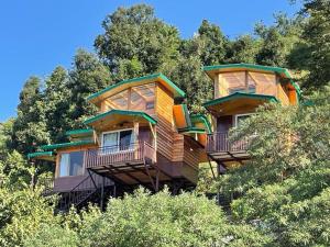 a tree house with balconies on top of trees at Atulyam, Pangot in Nainital