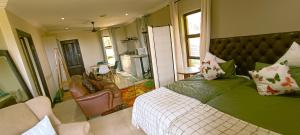 een slaapkamer met een bed, een bank en een stoel bij The Zen Den in Durban