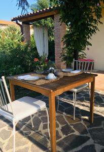 a wooden table with two white chairs and a table with food at Podere Gradisca in Alberese