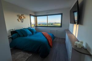 Un dormitorio con una gran cama azul y una ventana en Vue à Couper le Souffle - Villa de Charme avec Spa en Bord de Mer - Pointe Finistère, en Plougonvelin