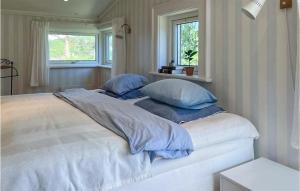 1 dormitorio con cama blanca y almohadas azules en Cozy Home In Domsj With Kitchen en Domsjö