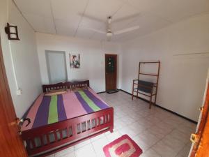 1 dormitorio con 1 cama y 1 silla en Bandula's Beach Inn en Hikkaduwa