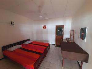Bandula's Beach Inn في هيكادوا: غرفة نوم فيها سرير وطاولة فيها