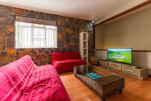 a living room with a red couch and a tv at Beachfront Tamarin Villa in Tamarin