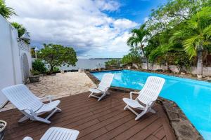 a patio with three chairs and a swimming pool at Beachfront Tamarin Villa in Tamarin