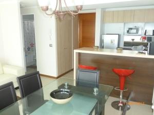 uma cozinha com uma mesa de vidro e cadeiras vermelhas em Laguna del Mar - La Serena em La Serena