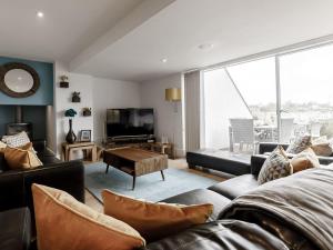 un soggiorno con divano e TV di Cotswolds Lakehouse, with hot tub & spa access, Lower Mill Estate a Somerford Keynes