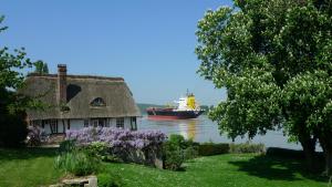 um barco na água com uma casa e um navio em La Bonne Auberge - Seine Panorama SAS em Vieux-Port