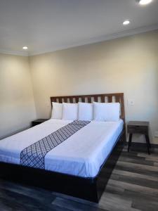 北山的住宿－Budget Inn，卧室配有一张带白色床单和枕头的大床。