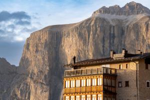 um edifício com uma montanha ao fundo em Hotel Pordoi Passo Pordoi Vegetarian Hotel em Canazei