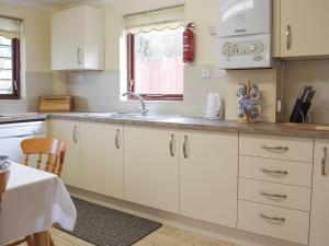 a kitchen with white cabinets and a sink at The Old Coach House in Hayscastle