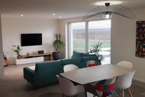 salon z zieloną kanapą i stołem w obiekcie Maison Passive avec piscine proche Colmar w mieście Logelheim