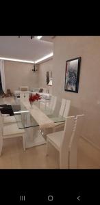 una sala da pranzo con tavolo in vetro e sedie bianche di Villa chic a Marrakech