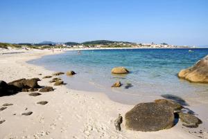 a beach with rocks and people in the water at Apartamento en las Rias Bajas in Ribeira