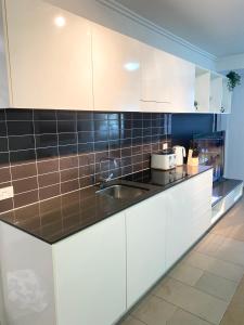 a kitchen with white cabinets and black tiles on the counters at Cozy Cool Getaway in Townsville