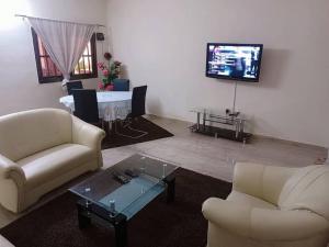 - un salon avec deux canapés et une télévision dans l'établissement Résidence aux deux cocos, à Lomé