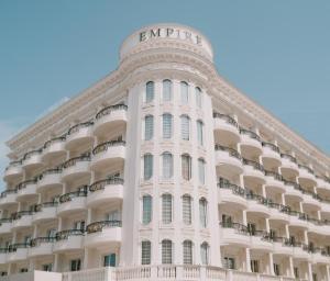 Un gran edificio blanco con un cartel en él. en Hotel Empire Albania, en Durrës