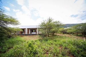 a house in the middle of a field with trees at Bushwillow Lodge, Royal Jozini PGR, eSwatini in Lavumisa