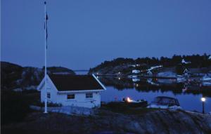 a house with a flag on top of a body of water at Holiday Home Flekkerøy Paulen in Mebø