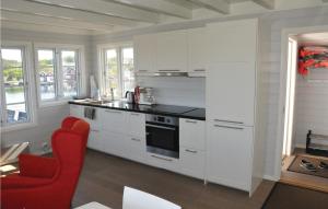 MebøにあるGorgeous Home In Flekkery With Wifiの白いキャビネットと赤い椅子付きのキッチン