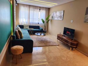 sala de estar con sofá azul y TV en Studio lumineux avec piscine/Gare casa oasis en Casablanca