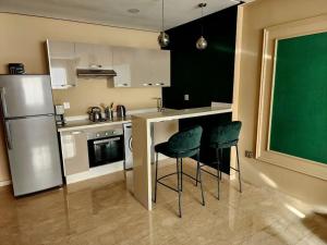 Studio lumineux avec piscine/Gare casa oasis في الدار البيضاء: مطبخ مع ثلاجة و كرسيين أخضر