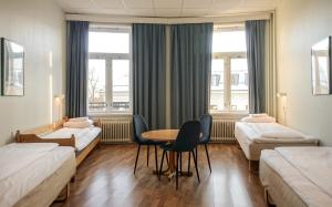 a room with two beds and a table and chairs at Cochs Pensjonat in Oslo