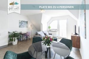 a living room with a glass table and green chairs at Semper Suite No2 - Ruhige 2 Zi FeWo 1-4 Pers mit Küche, Duschbad, Balkon und Parkplatz in Hofgartennähe in Bayreuth