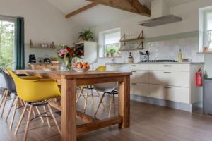 a kitchen with a wooden table and yellow chairs at Natuurhuis Dichtby in Rucphen