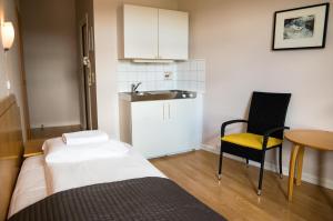 a small room with a bed and a chair and a sink at Cochs Pensjonat in Oslo