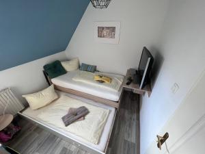 Habitación pequeña con 2 camas y TV. en Ferienhaus am Mühlgraben en Thale