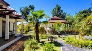 a house with a courtyard with palm trees at Isan Golf & Adventure Hotel in Udon Thani