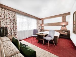 a living room with a bed and a table and chairs at Hotel Lärchenhof in Kaunertal