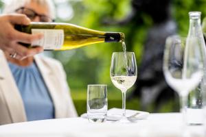 une femme versant du vin blanc dans un verre de vin dans l'établissement Hotel Refsnes Gods - by Classic Norway Hotels, à Moss