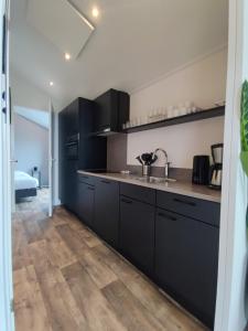 a kitchen with black cabinets and a sink at Chalet IJssel Eilanden Kampen Waterfront Airco in Kampen