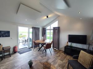 a living room with a table and chairs and a television at Familien und Angelurlaub Overijssel Chalet direkt am Wasser mit eigenem Bootsteg in Kampen