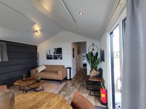 a living room with a couch and a table at Familien und Angelurlaub Overijssel Chalet direkt am Wasser mit eigenem Bootsteg in Kampen +10 photos