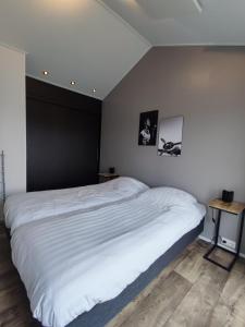a bedroom with a white bed with a black wall at Familien und Angelurlaub Overijssel Chalet direkt am Wasser mit eigenem Bootsteg in Kampen