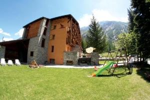 a man standing in front of a house with a playground at Green Hotel Herbetet in Cogne