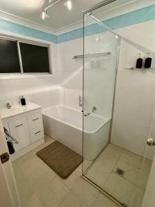 a bathroom with a shower and a tub and a sink at Cozy 3br house 100m to the lake in Chittaway Point