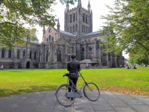 a statue of a person holding a bike in front of a cathedral at No 8 in Kington