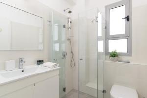 La salle de bains blanche est pourvue d'un lavabo et d'une douche. dans l'établissement Deluxe & Terrace with City Overview by FeelHome, à Holon