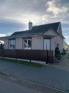 a white house with a fence in front of it at Cozy apartment in Karmelava in Karmėlava