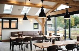 a restaurant with tables and chairs and windows at Cotswolds Lakehouse, with hot tub & spa access, Lower Mill Estate in Somerford Keynes