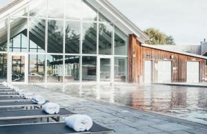 a large glass building with benches in front of it at Cotswolds Lakehouse, with hot tub & spa access, Lower Mill Estate in Somerford Keynes