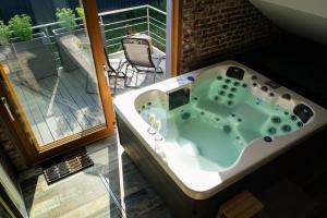 a bath tub sitting on a balcony next to a window at Spa privatif à la ferme - Haut de gamme - Atypique in Bois-Grenier